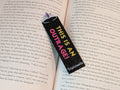 Black rectangle bookmark with a tiara icon on the end with a purple jewel in the middle. Text on the bookmark reads "THIS IS AN" in yellow and "OUTRAGE!" in magenta.