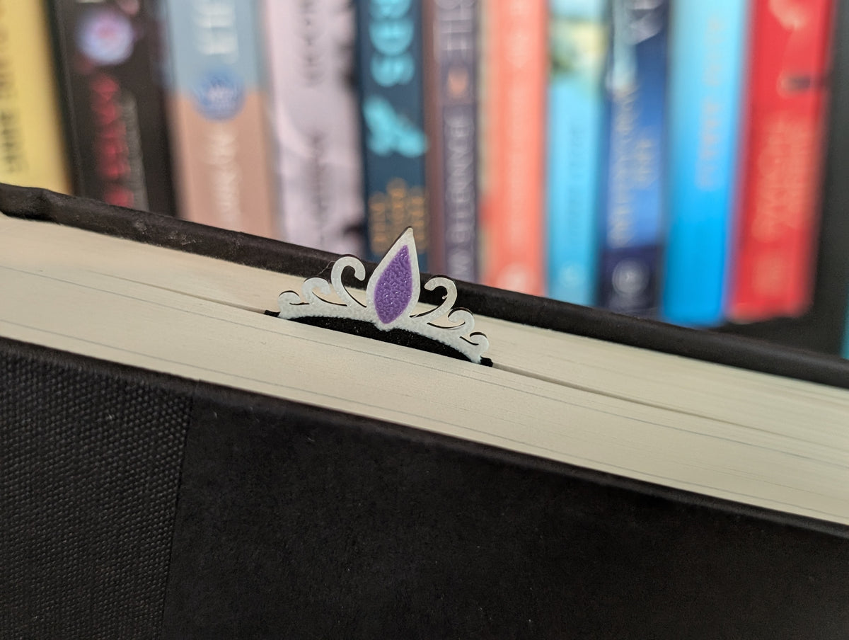 Tiara icon with purple jewel sticking out of the top of a book